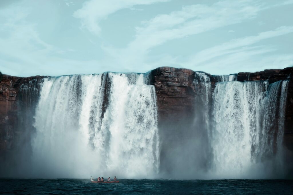 pexels-photo-1830721-1830721 A breathtaking waterfall with kayakers navigating the waters below, showcasing nature's beauty.