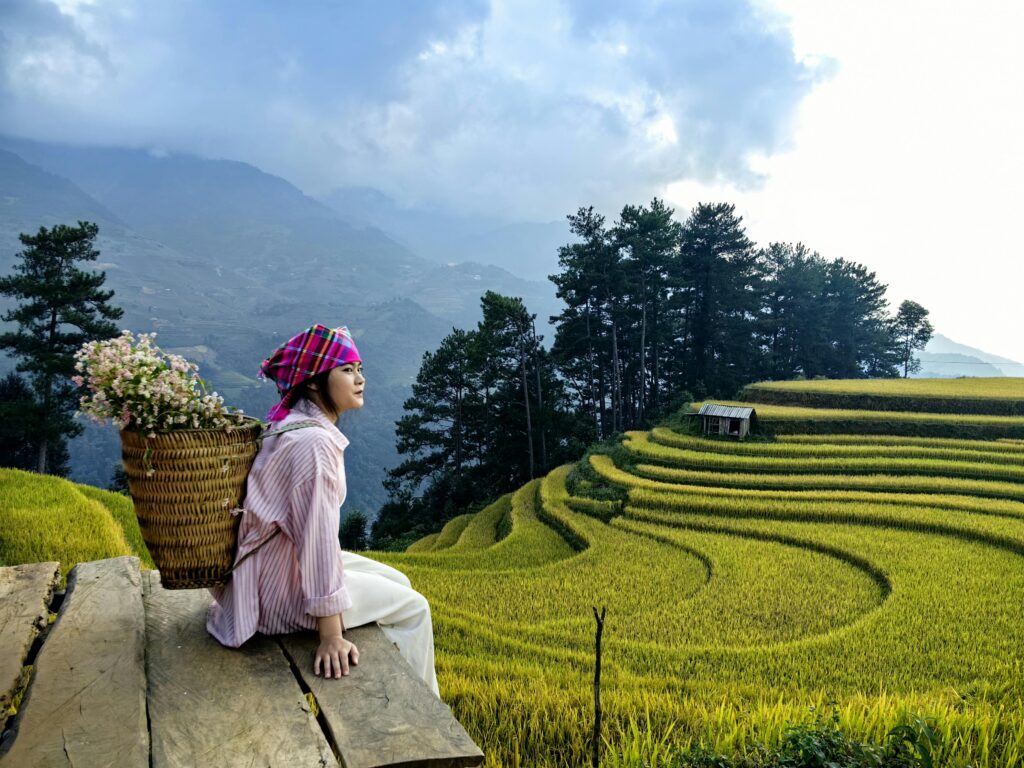 pexels-photo-28902631-28902631 Hmong woman with flowers beside stunning Yên Bái rice terraces, Vietnam.